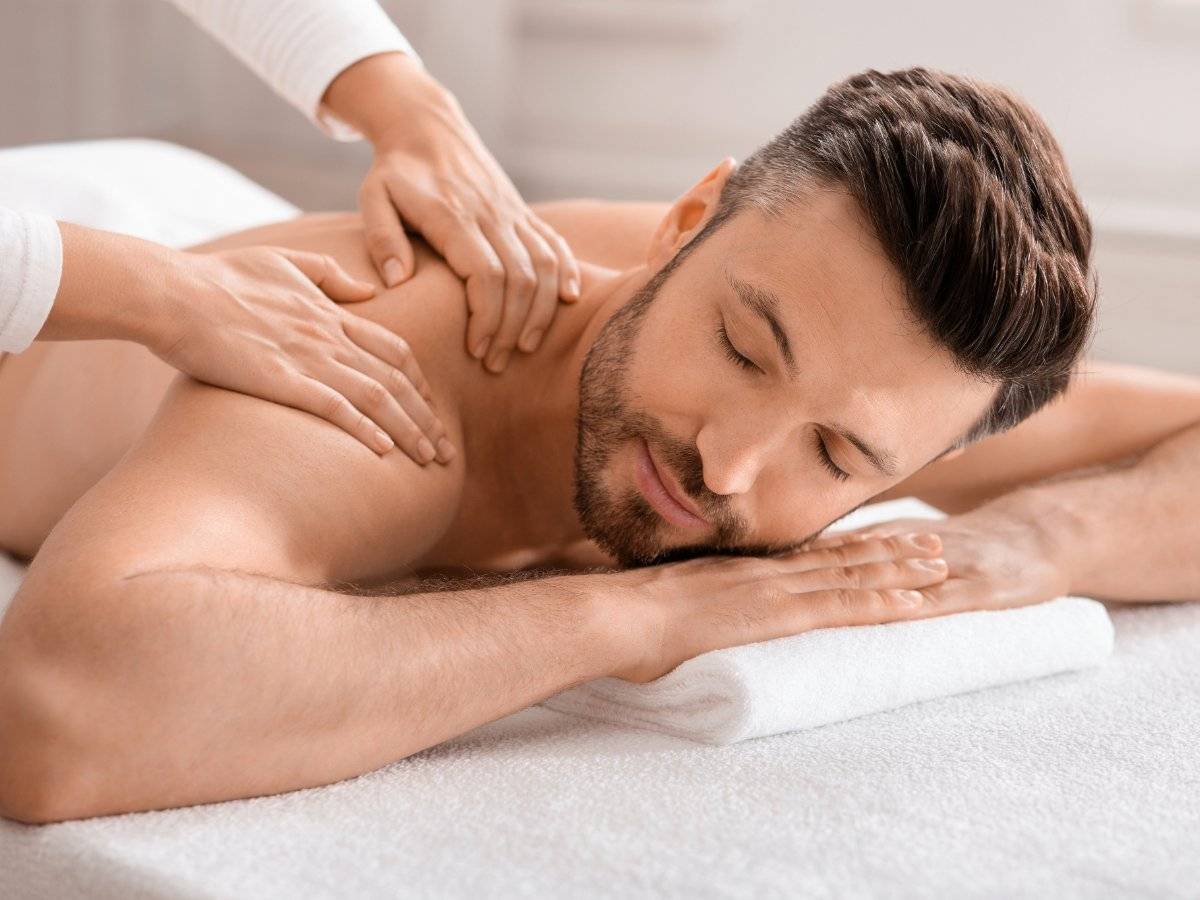 Man receiving a relaxing shoulder massage in a bright spa setting.