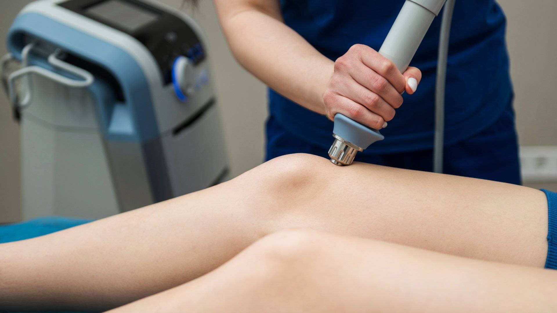 A healthcare professional administering shockwave therapy on a patient's knee.