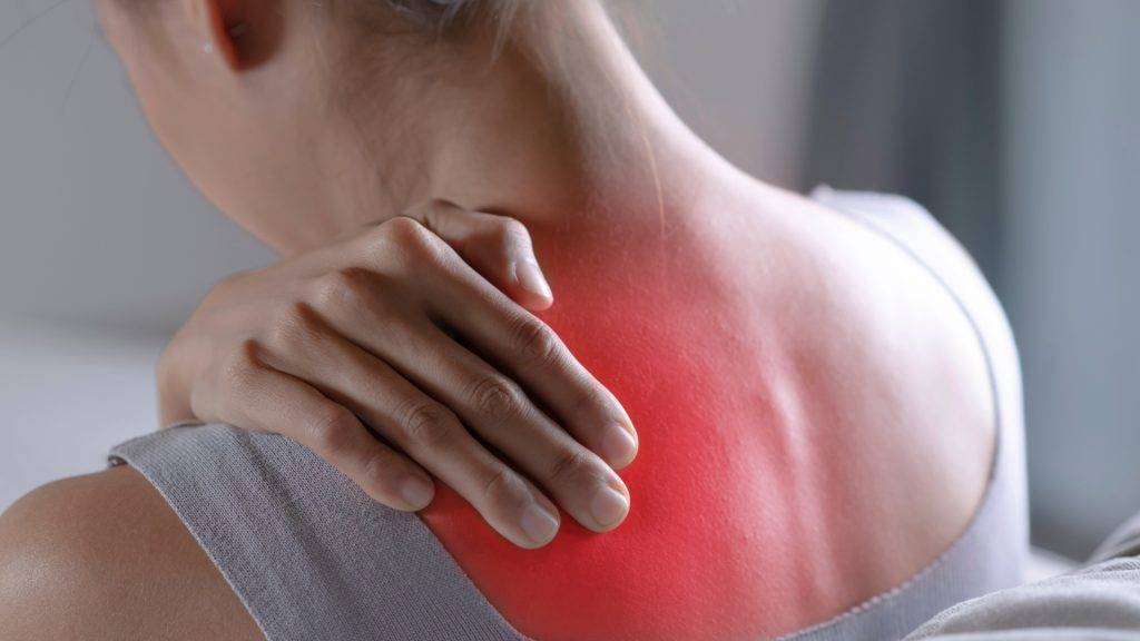 Person touching their shoulder with a red area indicating widespread pain