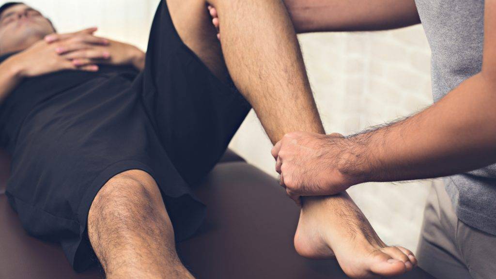 Physiotherapist performing a leg mobilisation technique during a therapy session