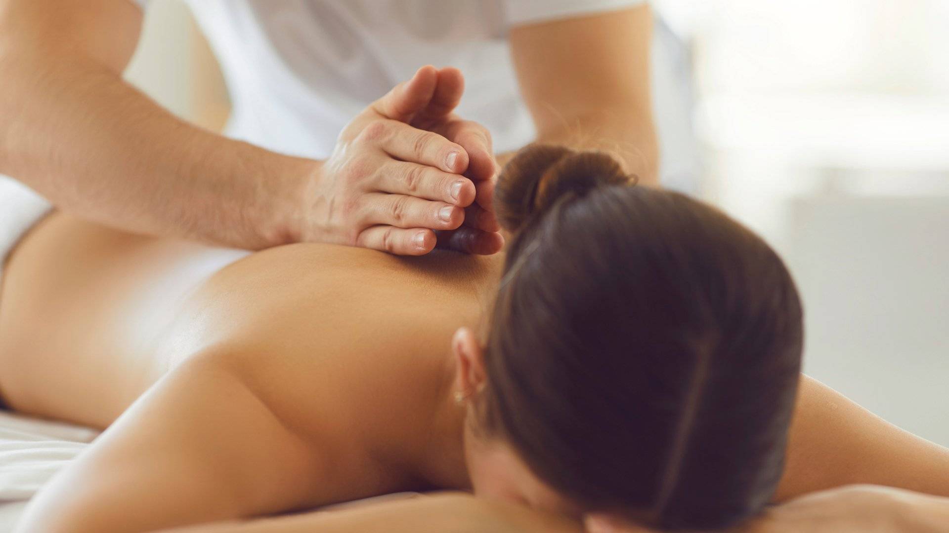 Therapist providing a back massage to a woman lying face-down in a peaceful setting