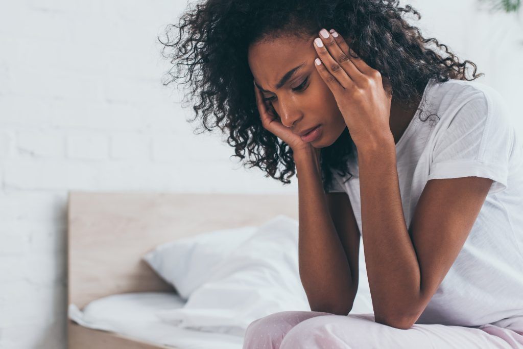 Woman holding her head in her hands with a painful migraine