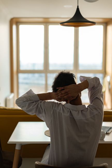 Person gently stretching their neck while seated at a home desk